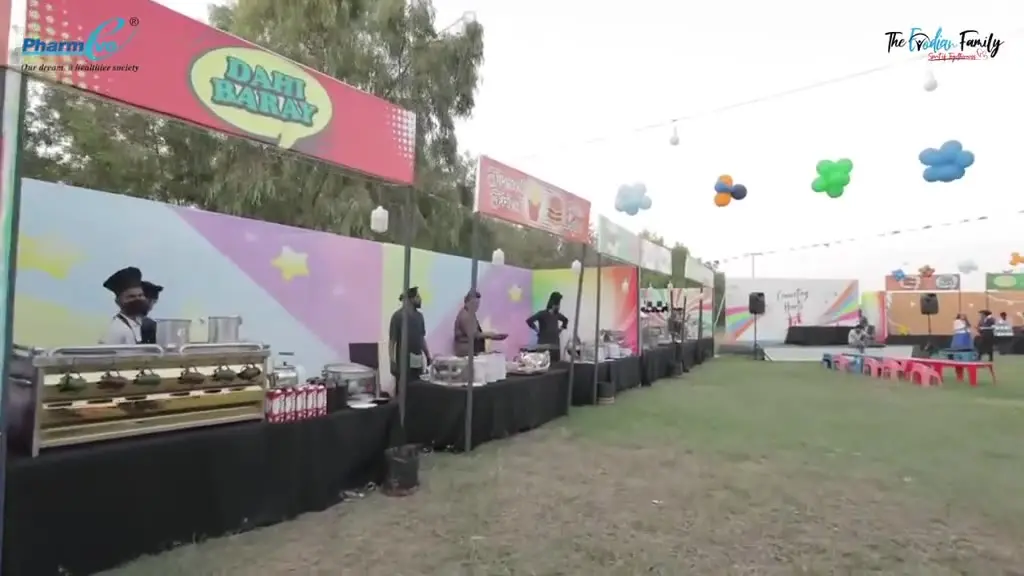Footage from the Connect Heart family event: an outdoor ground laid out with a long run of brightly branded activity and catering stalls, bunting strung overhead and balloon decoration along the walkway.